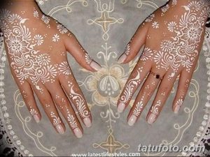 Фото белых татуировок хной на руках девушки. Сложные восточные узоры, напоминающие кружево, покрывающие ладони и тыльные стороны рук.