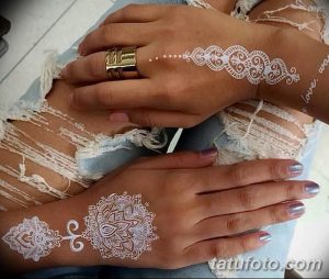 Фото парных белых татуировок хной на руках двух девушек. Сложные восточные узоры с цветочными и геометрическими элементами.