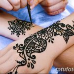 Фотография изящной татуировки хной, нанесенной на руку. Мастер продолжает работу над рисунком.