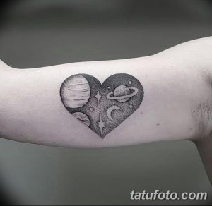 Фотография татуировки на предплечье, изображающей сердце, внутри которого находятся планеты и звезды. Оригинальный и красивый рисунок.