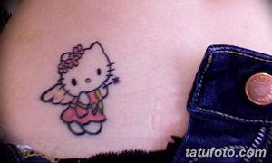 Фото тату: маленькая татуировка в виде Hello Kitty, расположенная на пояснице. Цветной рисунок татуировки.