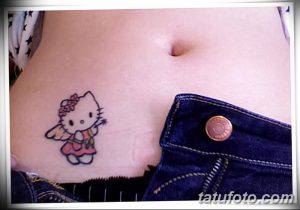 Фото тату Hello Kitty с крылышками на животе. Нежный и забавный рисунок татуировки в мультяшном стиле.