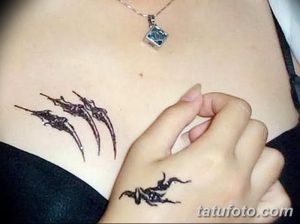 Фото тату в стиле трайбл на груди и руке. Черный рисунок татуировки с острыми углами и сложным узором.