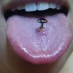 Фото пирсинга языка с черным драгоценным камнем. Гладкий черный камень вставлен в пирсинг языка, создавая элегантный и минималистичный вид.