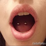 Фото тату пирсинга языка с двумя серебристыми шариками. Крупный план демонстрирует открытый рот и проколы языка.