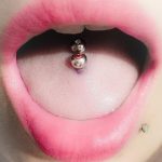 Фото пирсинга языка с серебристым шариком. Нежный розовый оттенок кожи и крупный план.