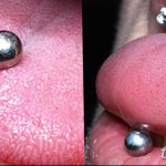 Фото двойного пирсинга языка с двумя серебристыми шариками. Крупный план демонстрирует два прокола и блеск украшений.