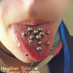Фото пирсинга языка: девушка демонстрирует 13 проколов, 12 вертикальных и 1 горизонтальный. Необычный и смелый вид модификации тела.