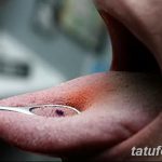 Фото тату: Крупный план языка, зажатого медицинским инструментом во время процедуры пирсинга. Видна подготовка к введению украшения.