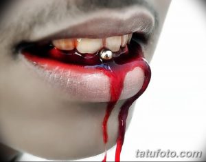 Фото тату пирсинга языка с кровью. Видны капли крови, стекающие с губы вокруг пирсинга.