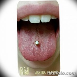 Фото пирсинга языка с золотым украшением. Язык высунут, демонстрируя пирсинг и белоснежные зубы. Стильный и привлекательный образ.