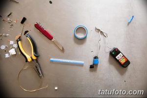 Фото различных инструментов для ремонта тату-машинки, разложенных на серой поверхности. Изображение для мастеров тату.