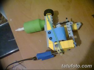 Фотография тату-машинки, собранной из деталей LEGO, лежащей на столе. Изображение демонстрирует креативность и необычный подход к созданию тату-оборудования.