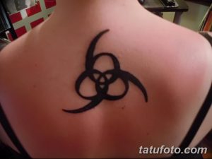 Фото татуировки с изображением символа группы Black Sabbath на спине. Стиль татуировки - минимализм, чёрный цвет.