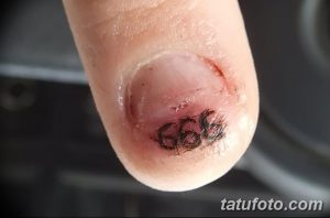 Фото татуировки на пальце: крошечное изображение числа 666. Минималистичный и незаметный дизайн, привлекающий внимание своей простотой.