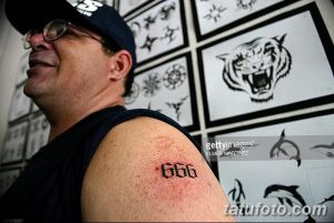 Фото татуировки с числом 666 на плече мужчины, сделанной в тату-салоне. Рисунок татуировки с темным значением.