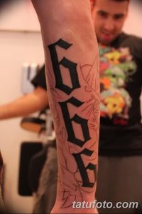 Фото тату с числом 666, выполненным готическим шрифтом на руке. Рисунок татуировки с темным, зловещим значением.