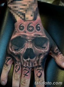 Фото татуировки с изображением черепа и числа 666 на руке. Черно-серый рисунок татуировки с детальной проработкой.