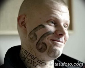 Фото татуировки с числом 666 на лице мужчины. Чёрный рисунок, вызывающий и провокационный символ, расположенный на щеке.