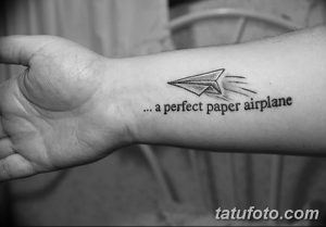 Фото тату: небольшой рисунок бумажного самолетика и надпись '... a perfect paper airplane' на запястье. Черно-белая графика, минималистичный стиль.