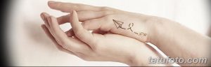 Фото тату на руке с изображением бумажного самолетика и фразой 'Let Go'. Минималистичный рисунок татуировки.