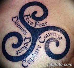 Фото тату трискеле на плече с надписями 'Face Fear', 'Dismiss Defeat', 'Capture Courage'. Черно-белый рисунок татуировки в стиле графика.