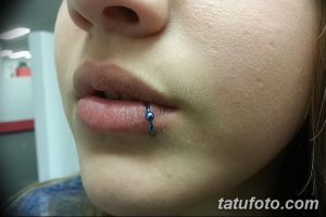 Фото пирсинга губы с синим украшением. Крупный план женской губы с аккуратным проколом и блестящим синим камнем. Идеально для поиска идей для пирсинга.