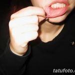 Фото тату: девушка держит губу, демонстрируя свежий пирсинг с небольшим металлическим кольцом. Видно место прокола и начальный этап заживления.