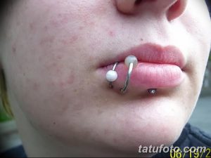 Фото тату: пирсинг губы с двумя жемчужинами и спиральным металлическим элементом. Крупный план женской губы с пирсингом.