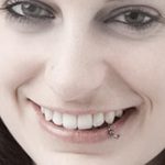 Девушка с проколом нижней губы, украшенным небольшой серебристой подвеской. Фото демонстрирует милый и привлекательный образ.