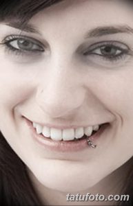 Девушка с проколом нижней губы, украшенным небольшой серебристой подвеской. Фото демонстрирует милый и привлекательный образ.
