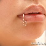 Фото пирсинга губы с серебряным кольцом. Крупный план женской губы с аккуратным пирсингом в центре нижней губы. Стильный и минималистичный дизайн.