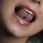 Фото пирсинга языка с серебряным шариком. Крупный план, демонстрирующий аккуратное отверстие и блеск металла. Подчеркивает индивидуальность и смелый стиль.