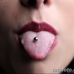 Фотография языка, проколотого вертикально. Виден серебряный металлический пирсинг. Крупный план демонстрирует необычный вид модификации.