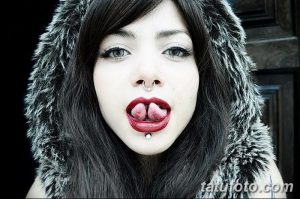 Фотография девушки с экстремальным пирсингом языка, создающим эффект расщепления. Видны металлические украшения и необычная форма языка.