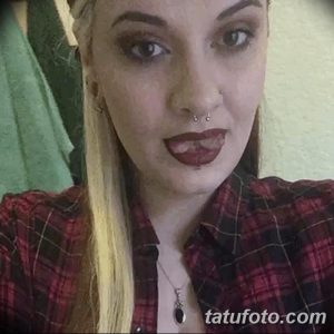 Фотография девушки с длинными светлыми волосами и татуировкой на шее. Татуировка представляет собой небольшой рисунок, добавляющий образу загадочности.