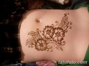 Фото временной татуировки хной на животе. Рисунок представляет собой нежный цветочный орнамент с акцентом на область пупка.