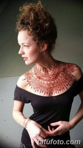 Фото тату мехенди на шее и груди с изображением сложного орнамента. Рисунок выполнен в красном цвете и выглядит очень эффектно и привлекательно.