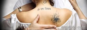 Фотография женщины с татуировками на спине и шее, изображающими цветок и надпись на санскрите. Идеально для поиска идей для тату в восточном стиле.