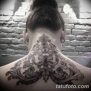 Черно-белая татуировка на шее и верхней части спины, изображающая сложный орнамент, выполненный в изящном стиле.