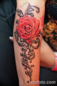 Фото тату: Красивая татуировка на предплечье, изображающая красную розу, окруженную изящным кружевным узором, выполненная в реалистичном стиле.