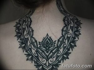 Фото тату: сложная татуировка в стиле мехенди, украшающая шею и ключицы. Черно-белый рисунок с растительными мотивами и узорами.