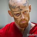 Фотография мужчины с татуировками, покрывающими его лицо. Татуировки выполнены в темных тонах и создают сложный и пугающий образ.