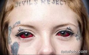 Фотография девушки с татуировками на лице и надписью "Devil's Reject" на лбу. Изображение демонстрирует экстремальный стиль модификации тела.