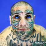 Фотография мужчины с полностью покрытым татуировками лицом. Изображение демонстрирует яркий и необычный стиль модификации тела.