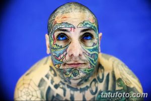 Фотография мужчины с полностью покрытым татуировками лицом. Изображение демонстрирует яркий и необычный стиль модификации тела.