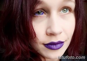 Фотография девушки с одним фиолетовым глазом и одним естественным. Яркий макияж губ и волосы.