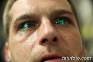 Фото тату вокруг глаз мужчины: темные линии, зеленые глаза, брутальный образ. Идеи для тату в стиле минимализм.