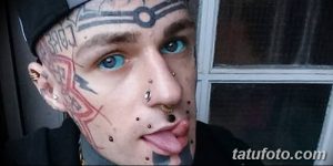 Фото тату: мужчина с татуировками на лице, включая брови, щеки и подбородок. Яркие цвета, абстрактные узоры и пирсинг.