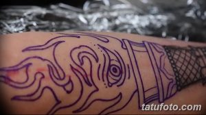 Фото эскиза татуировки на руке с изображением факела и мистических символов. Фиолетовый рисунок татуировки на коже.